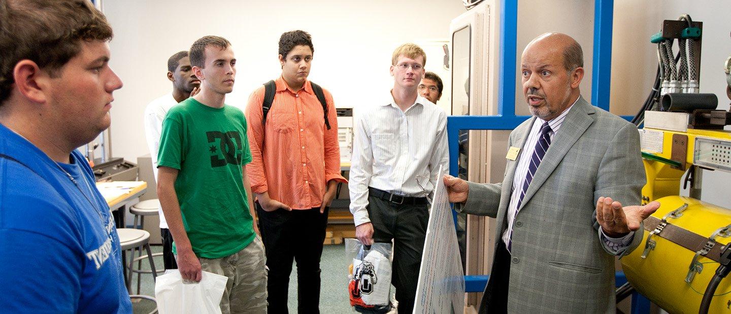 A professor talking to a group of students in a research lab.